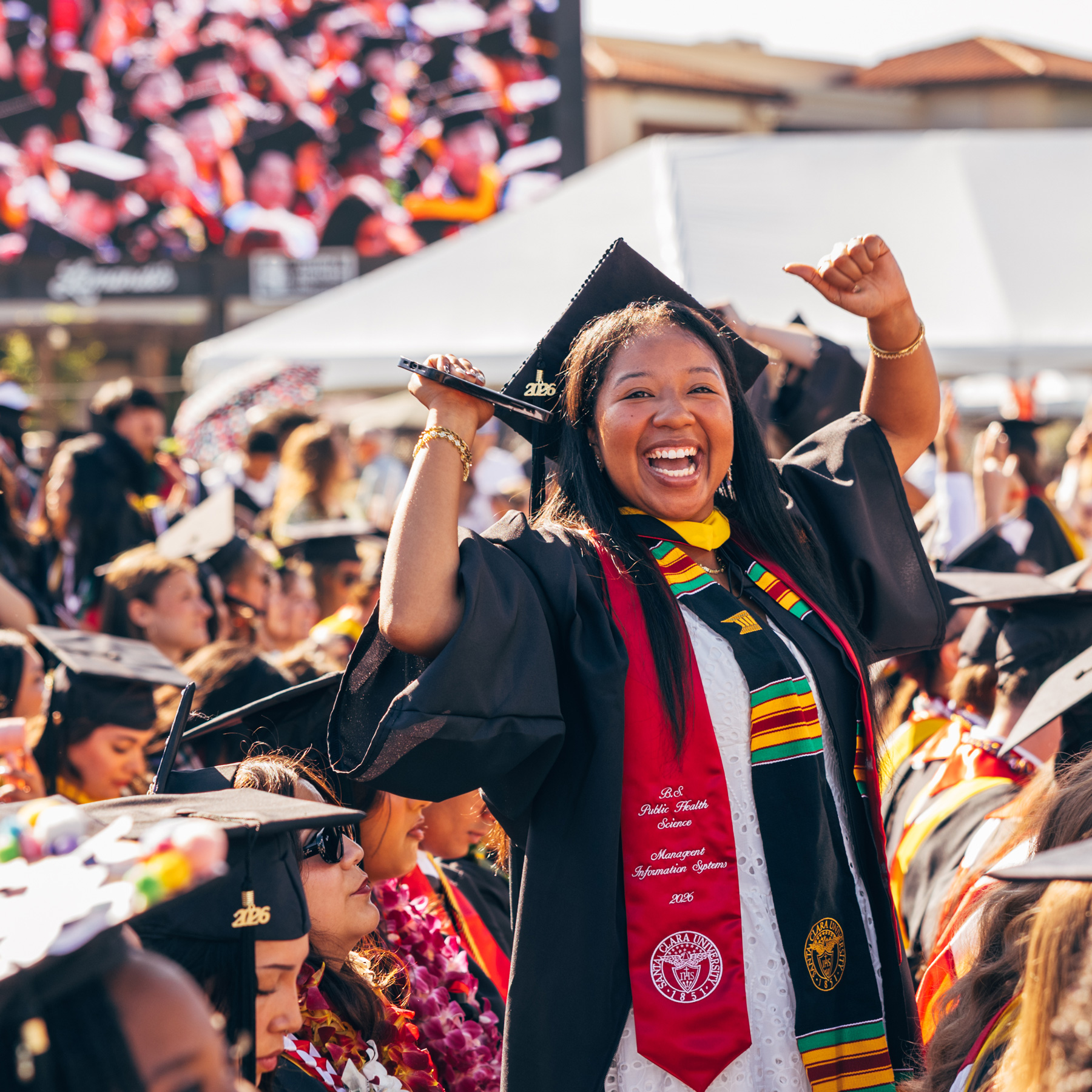 Graduate in regalia cheers during Santa Clara University Commencement.
