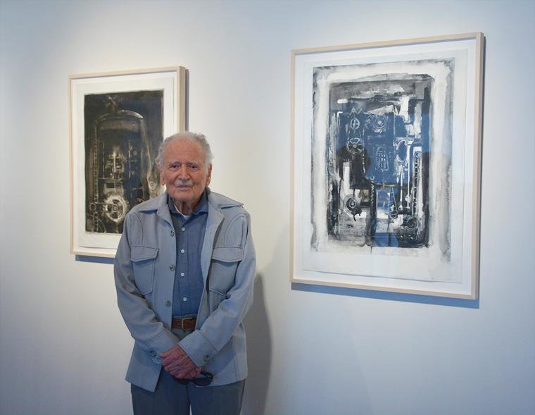Artist Joseph Zirker standing with two of his artworks.