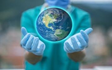 medical professional with outstretched hands holding a globe