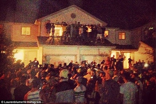 Large crowd gathered outside of a house at night image link to story