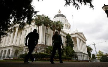 Two people walk near the California State Capitol Building.