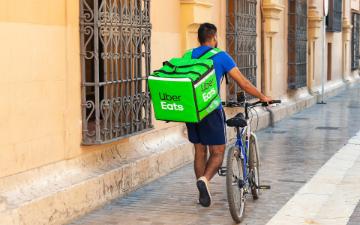 man on bicycle delivers food for Uber Eats image link to story