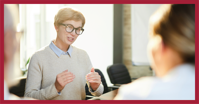 Corporate leader talking to onlooking professionals in a boardroom