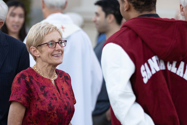 SCU President Julie Sullivan speaks with a student athlete after mass