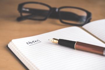 Fountain pen with lined notebook and glasses. Photo by David Travis, Unsplash.