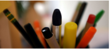 Close-up of various pens and pencils in a holder.