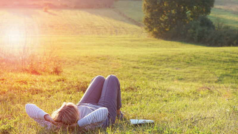 Woman lying on her back in a sunny meadow