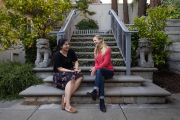 Two students sit at the bottom of building steps 