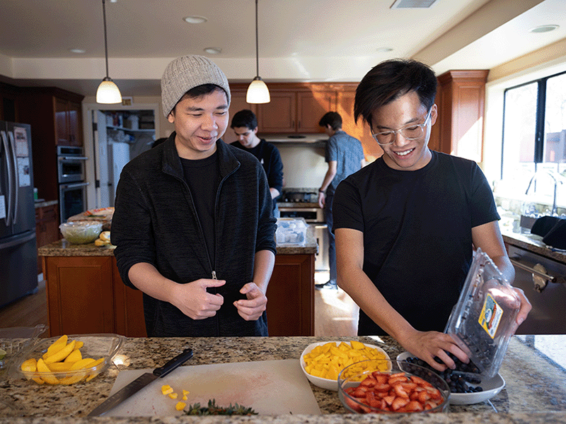 Nicholas Truong and friend preparing food in the kitchen.