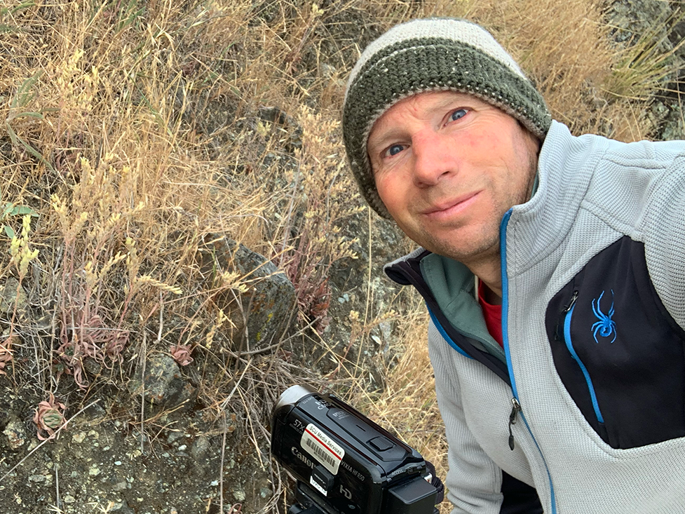 Professor Justen Whittall outdoors with video camera set up to capture local succelents.