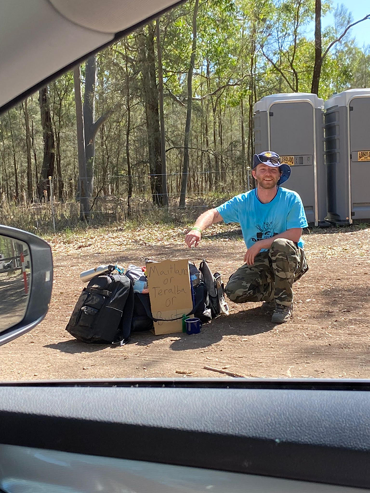 Brendan viewed through a car window, outdoors next to his equipment.