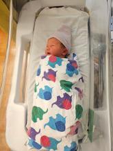 A newborn baby in a hospital crib