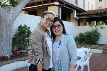 Two women posing and smiling outdoors in a backyard. 