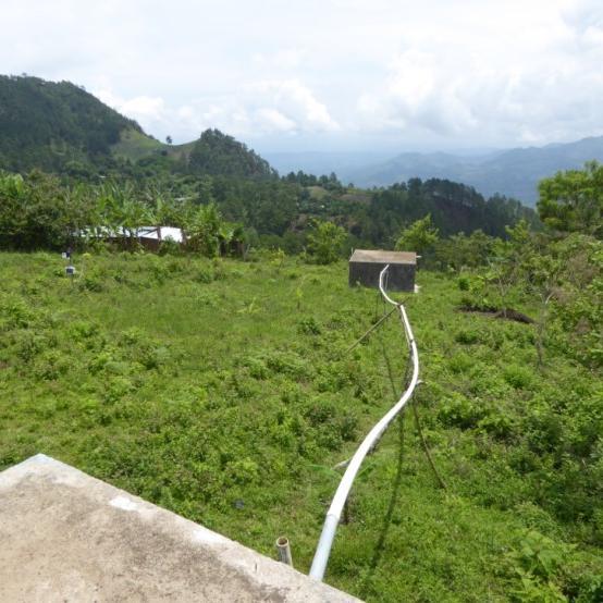 View of lush green hills with irrigation pipes connecting to houses image link to story