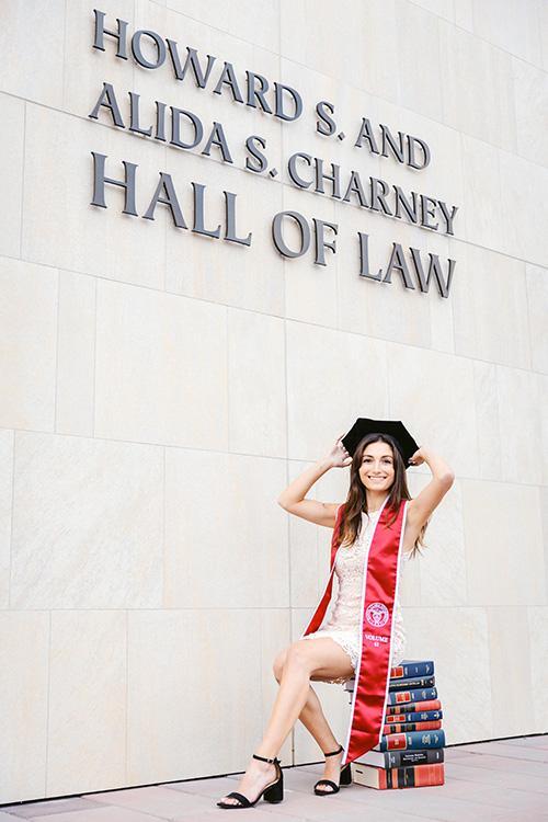 Elia Kazemi in graduation attire in front of Hall of Law sign image link to story