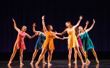 A group of dancers performing on stage in colorful costumes. 