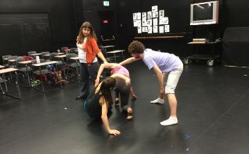 Three people in a dance class practicing movements. 