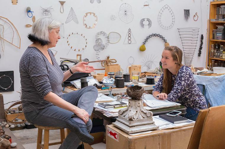 Student talking with artist Mari Andrews in her studio.