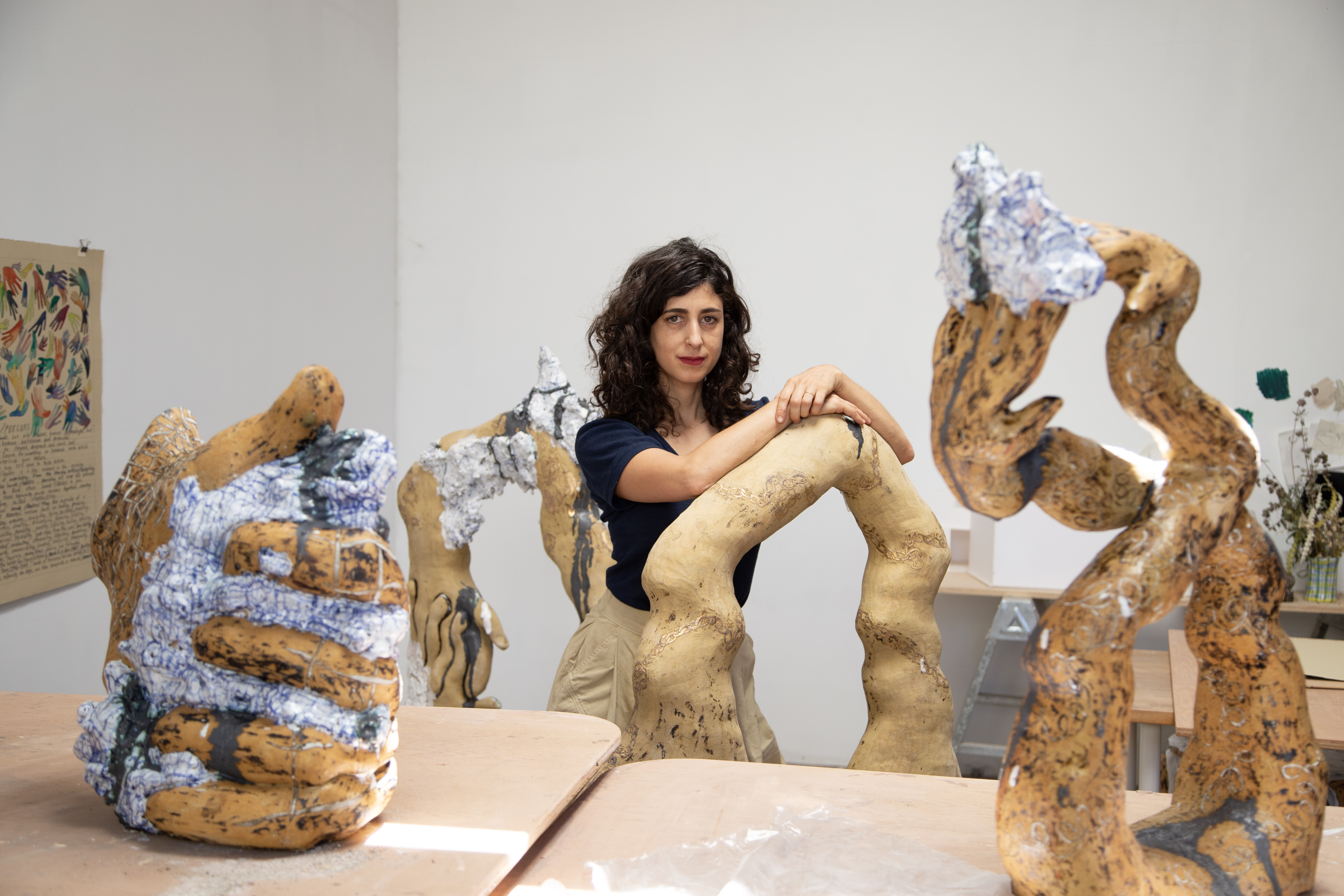 Female with dark brown hair standing in studio among large ceramic artworks