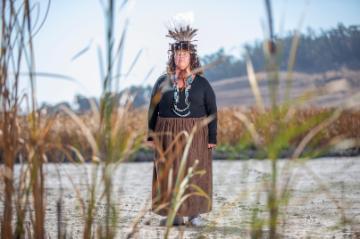 Woman wearing regalia standing in field