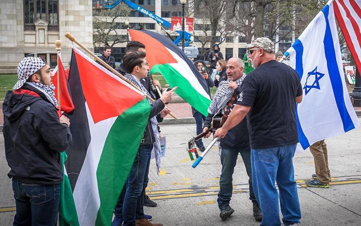 Two groups of protesters carrying Palestinian and Israeli flags facing off during an outdoor protest. Photo by Ted Eytan 2017.03.26 Anti-Israel Protest, Washington, DC. Used with permission under Creative Commons license CC BY-SA 4.0.