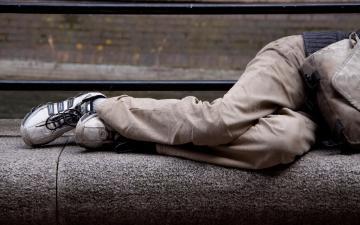 Unhoused person sleeping on cement steps. 