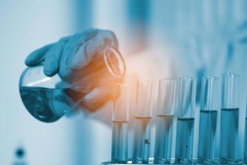 Laboratory researcher or doctor pouring solvent into a test tube. Image by crizzystudio via Adobe Stock.