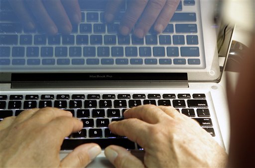 Hands typing on a laptop with code on the screen.