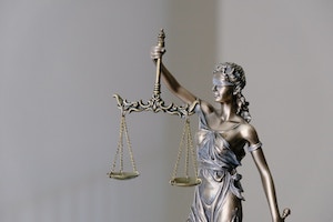 Sculpture of Lady Justice holding a sword and unbalanced scales 
