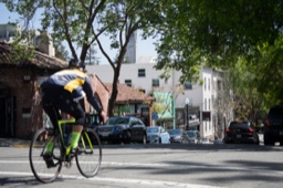 a bicyclist rides down the street in front of shops in Berkeley