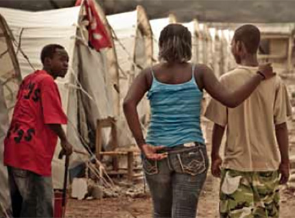 Several people standing in front of makeshift tents in Haiti.