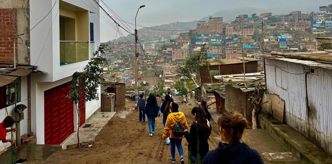 Peru Immersion 2024 students walking through neighborhood with hill of houses in the background