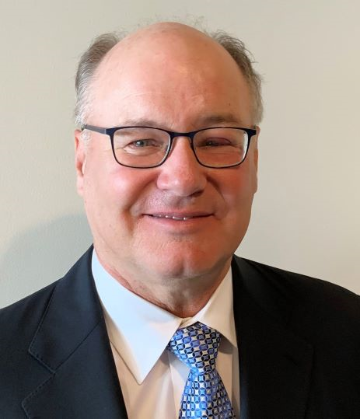A person named Larry T. Nally wearing glasses, a suit, and a tie.
