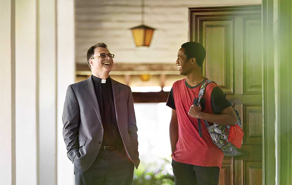 Jesuit priest and student laughing 