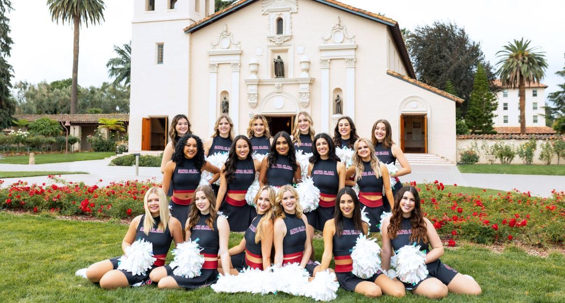 SCU Dance team poses together in their red and black uniforms in front of the Mission Church. 