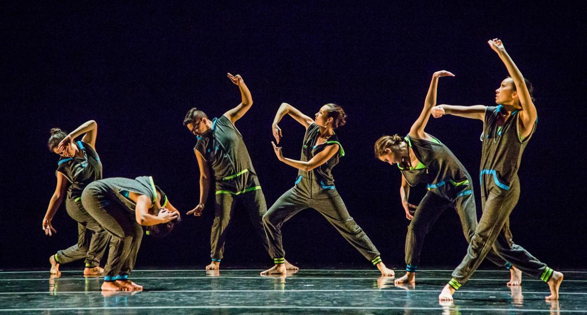 SCU dance students in matching outfits and in various poses on stage 