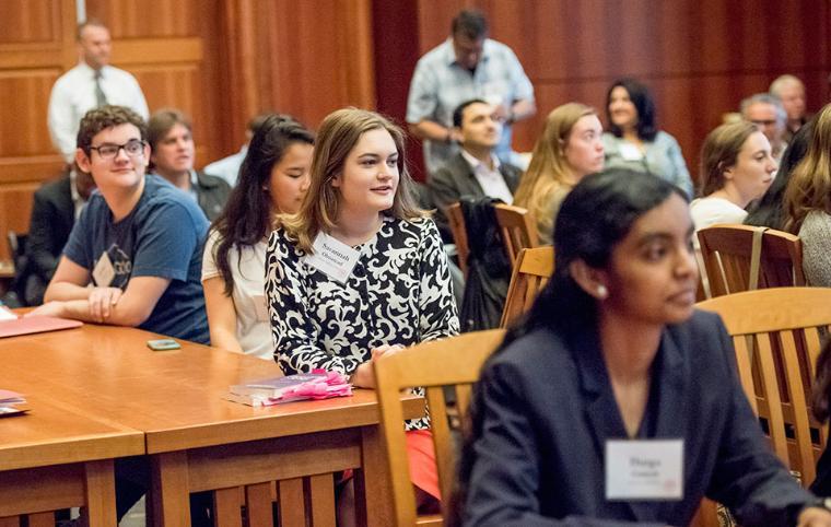 Students sitting at desks in a wood-paneled room with 