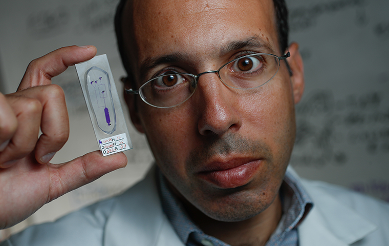 Paul Abbyad holding a microfluidic device 