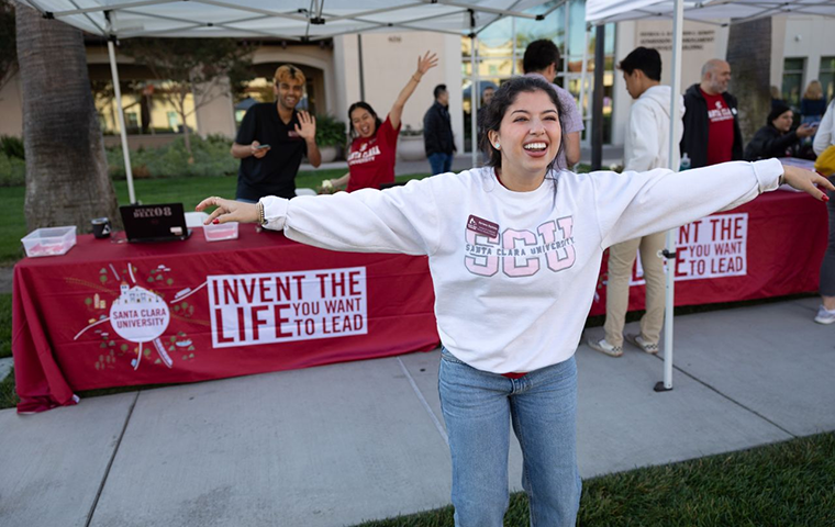 Student with arms outstretched in front of a table saying Live the Life You Imagine