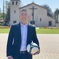 Leonard Lun standing in front of Mission Church holding a ball