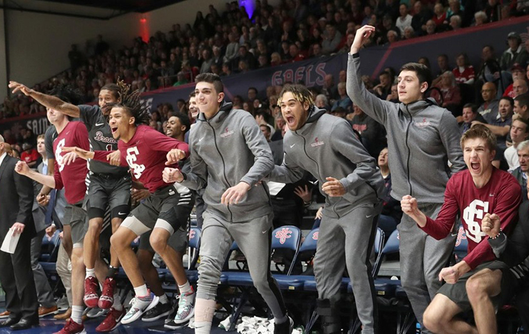 The men's basketball bench erupts in celebration against St. Mary’s