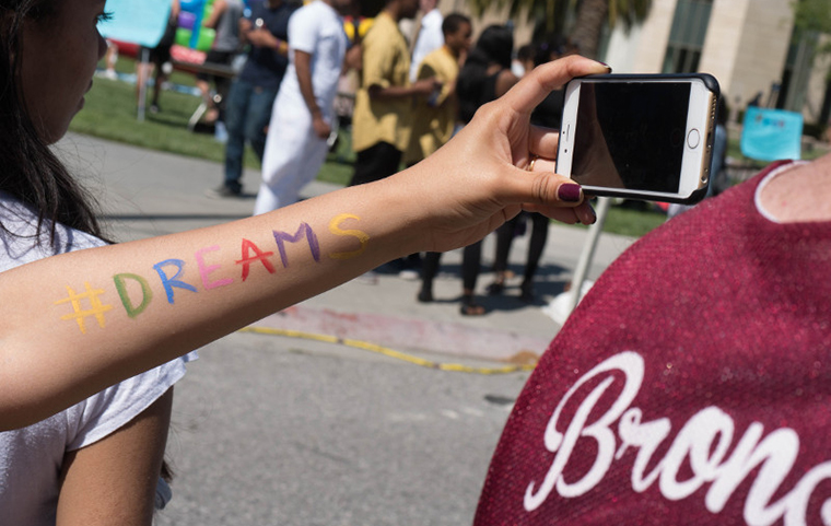 Student holding phone with selfie, arm painted with the word 