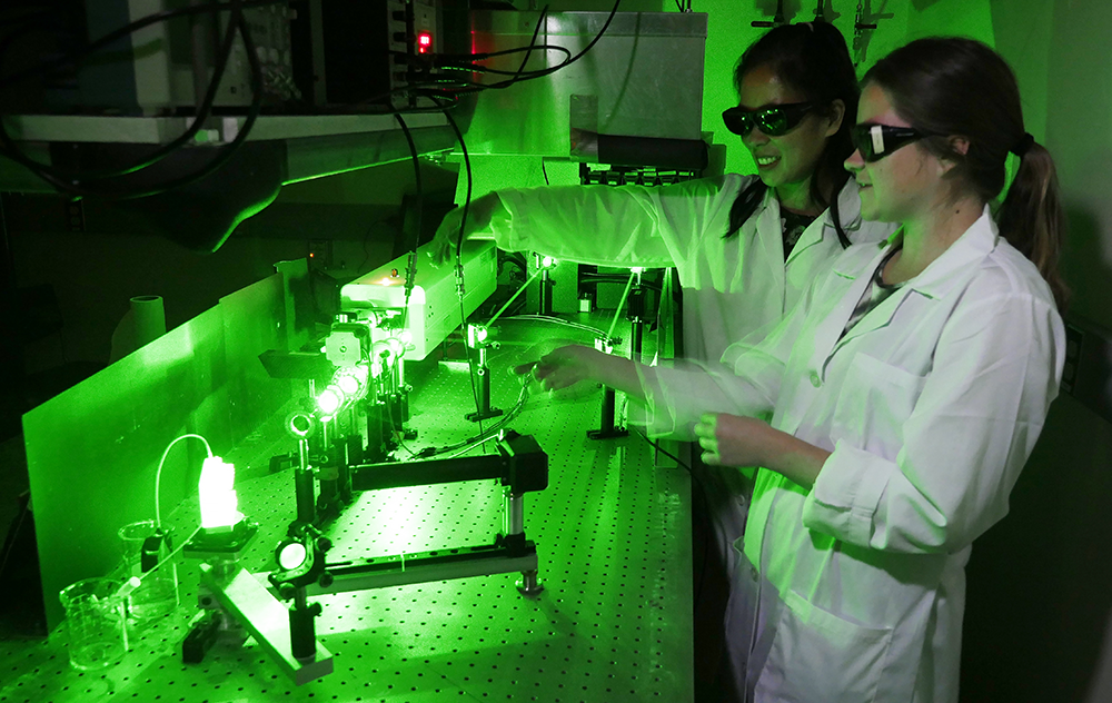 Grace Stokes and Jacenda Rangel perform research on cell membranes with green lasers. 