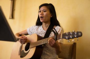 a student plays the guitar and sings in the jst chapel 