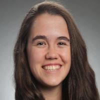 A person smiling with a grey background.