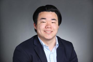 A man smiling in a formal portrait setting.