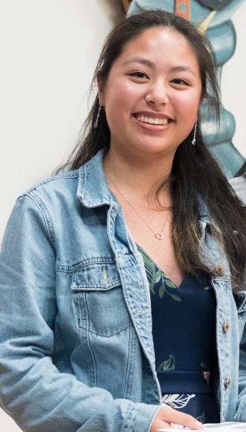 A person smiling, wearing a denim jacket.