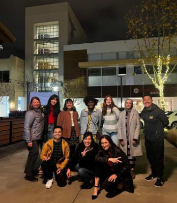 A group of people posing outdoors in an urban area at night.