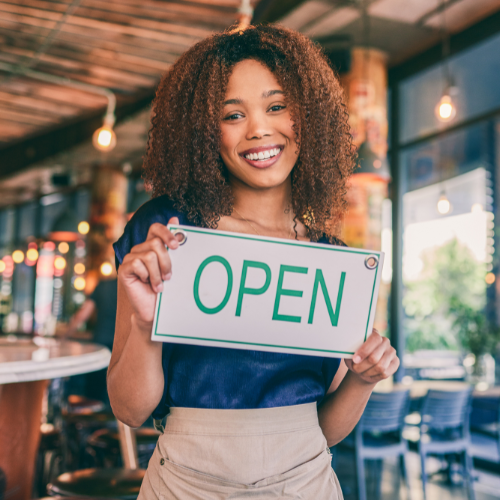 Image of business owner holding open sign 