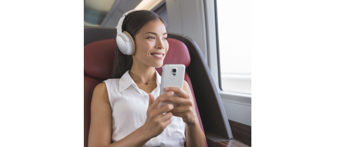 Photo of woman commuting and watching a phone with a headset on